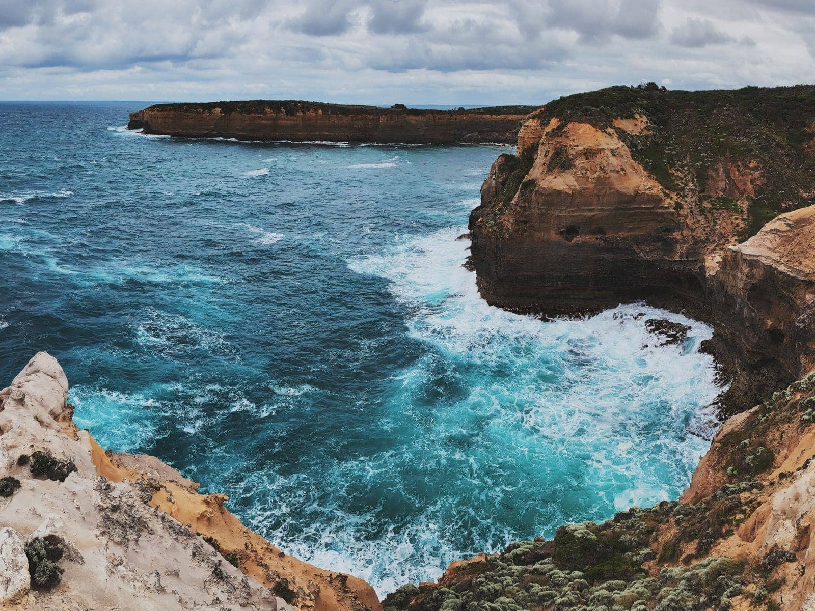 Turquoise water surging into a limestone gorge below sheer cliffs on the shipwreck coast